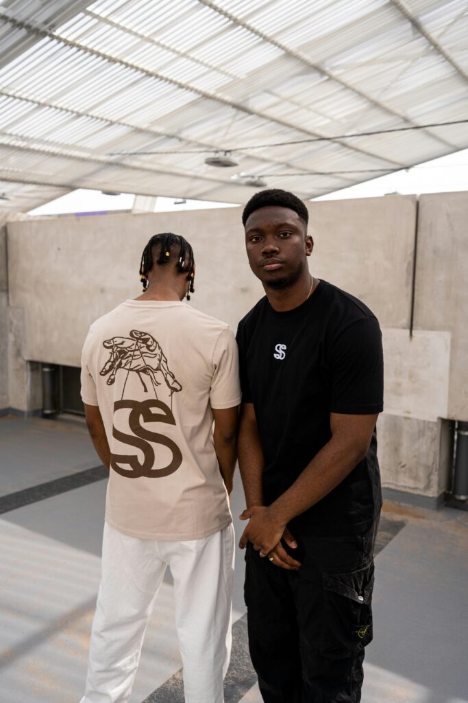 Two young men in stylish streetwear pose in a modern indoor setting in Bordeaux.